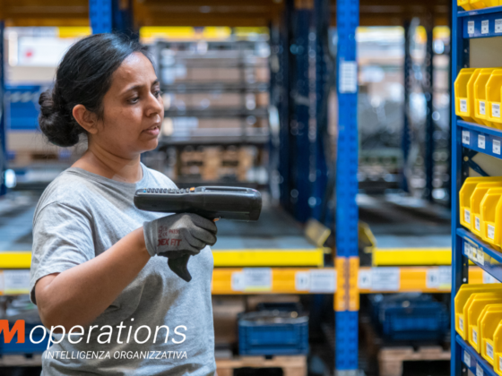 Operatrice logistica impegnata nel picking per l'outbound omnicanale in un magazzino 3PL, utilizzando un terminale WMS per la gestione delle scorte e il fulfillment e-commerce.