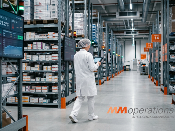 Operatrice logistica in camice bianco controlla l'inventario farmaceutico con tablet in un magazzino automatizzato a temperatura controllata.Titolo (Title)